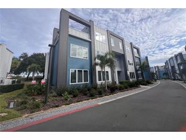 Modern three-story townhome with blue and gray siding at 7740 Sandy Ridge Dr # 217, Reunion, FL 34747