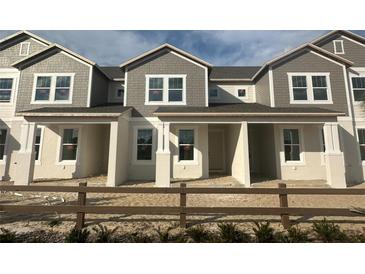 Charming townhome showcases a modern facade with neutral tones, inviting covered porch and professionally landscaped yard at 14038 Scarlet Aster Aly, Winter Garden, FL 34787