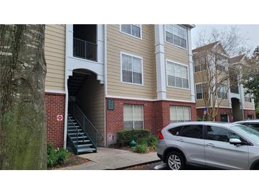Tan building exterior with red brick accents and green stairs leading to upper units for easy access at 13103 Mulberry Park Dr # 824, Orlando, FL 32821