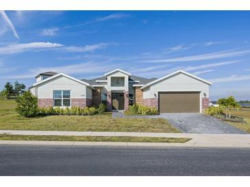One-story home with brick accents and a two-car garage at 208 Snowy Orchid Way, Lake Alfred, FL 33850