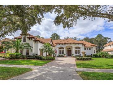 Beautiful two-story home with a tile roof, lush landscaping, and a brick paved driveway at 6130 Blakeford Dr, Windermere, FL 34786