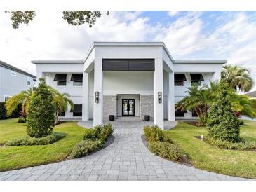 Modern two-story home with a white facade, gray stone accents, and a landscaped lawn at 6000 Tarawood Dr, Orlando, FL 32819