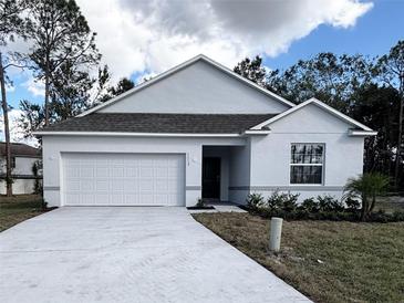 Newly constructed home with a white exterior, two-car garage, and landscaped front yard at 1112 Camden Way, Poinciana, FL 34758