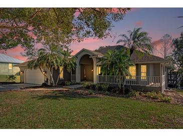 Charming single Gathering home with lush landscaping, mature palms, and a welcoming front porch at 128 W Juliana Way, Auburndale, FL 33823