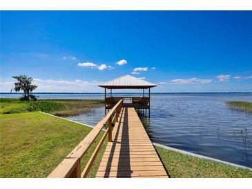 Picturesque waterfront view of a private dock with a covered gazebo on a sunny day at 2205 Cypress Cove Dr, Tavares, FL 32778