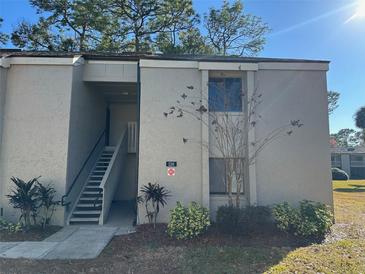 Exterior view of a well-maintained two-story condo with staircase, neat landscaping, and clear unit number at 126 Springwood Cir # B, Longwood, FL 32750