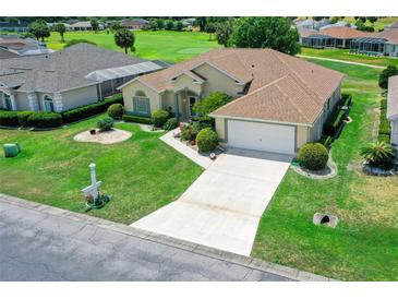 Home featuring an attached garage, meticulously maintained lawn, and vibrant flower beds at 2172 Nw 50Th Cir, Ocala, FL 34482