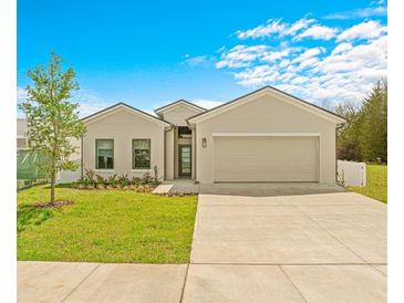 Tan house with a two-car garage and landscaping at 6360 Chorus Dr, Mascotte, FL 34753