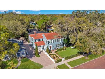 Charming two-story home features a brick driveway, red roof, manicured lawn, white picket fence, and lush, mature landscaping at 809 E Ridgewood St, Orlando, FL 32803