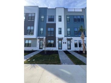 Modern townhouses with gray and white exterior, landscaping, and walkways at 2018 Packing District Way, Orlando, FL 32804