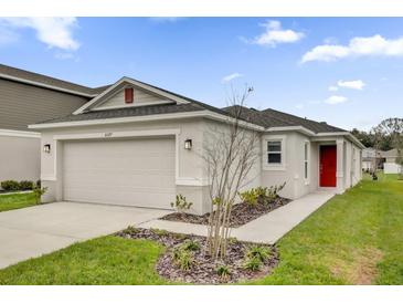 Charming one-story home with a two-car garage, a red door, and a well-maintained front yard at 8377 Wilder Pines Ave, Lakeland, FL 33809