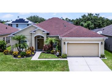 Charming single Gathering home features a well-manicured lawn, tropical landscaping, and attached two car garage at 17843 Golden Leaf Ln, Orlando, FL 32820