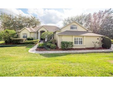 Charming home with a well-manicured lawn, lush landscaping and a brick walkway leading to the entrance at 11602 Graces Way, Clermont, FL 34711