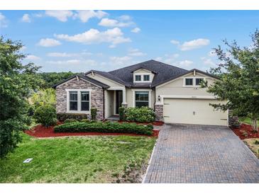 Single-story home with stone accents, landscaping, and a paved driveway at 30215 Bretton Loop, Mount Dora, FL 32757