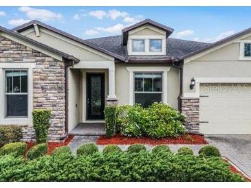 Charming single-story home featuring stone accents, a well-manicured lawn and a two car garage at 30215 Bretton Loop, Mount Dora, FL 32757