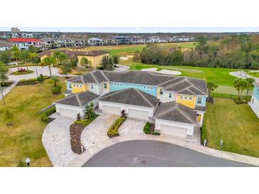 Aerial view of a four-unit townhome community with attached garages and a golf course view at 880 Driving Range Ct, Reunion, FL 34747