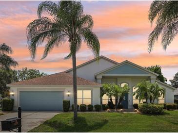 Charming single-story home featuring a well-manicured lawn and beautiful tropical landscaping at sunset at 9226 Longfellow Pl, Apopka, FL 32703