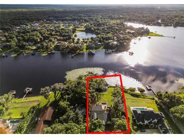 Aerial view of a waterfront house with a private dock and lush landscaping at 1700 Lake Markham Rd, Sanford, FL 32771