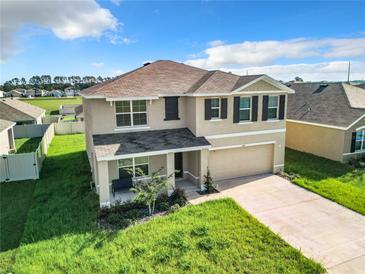 Two-story house with a neutral color scheme, a two-car garage, and a well-maintained lawn at 5043 Sw 88Th Pl, Ocala, FL 34476