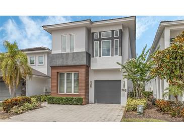 Modern two-story home with gray and wood accents, two-car garage, and landscaped front yard at 748 Desert Mountain Ct, Reunion, FL 34747