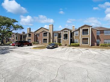 Attractive apartment building exterior showcasing a well-maintained facade and ample parking on a sunny day at 4367 Thornbriar Ln # 108, Orlando, FL 32822