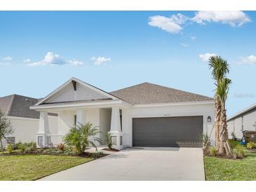 Charming single-story home with a well-manicured lawn, covered porch, and attached two-car garage at 4672 Ackee Rd, Kissimmee, FL 34758