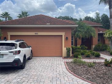 Home exterior featuring a red tile roof, brick driveway, and well-maintained landscaping at 681 Coronado Dr, Kissimmee, FL 34759