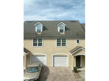 Well-maintained townhome with brick driveway, attached garages, and dormer windows providing natural light at 3432 Westchester Square Blvd # 205, Orlando, FL 32835