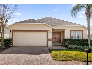 One-story house with beige exterior, brown accents, and a two-car garage at 313 Kensington Dr, Davenport, FL 33897