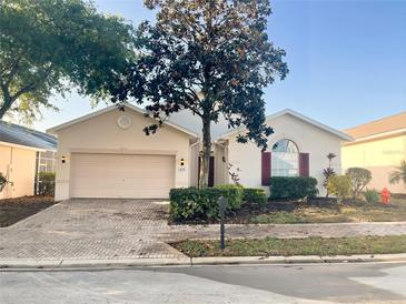 Charming single-story home featuring a brick driveway, arched window, and mature landscaping at 475 Windsor Pl, Davenport, FL 33896