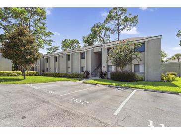 Exterior view of condo building with parking and landscaping at 115 Springwood Cir # C, Longwood, FL 32750