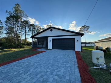 Charming home featuring a modern white and black color scheme, brick driveway, and manicured lawn at 1102 East Pkwy, Deland, FL 32724