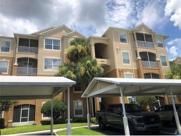 Beige condo building with screened balconies, palm trees, and carport parking at 6451 Old Park Ln # 110, Orlando, FL 32835