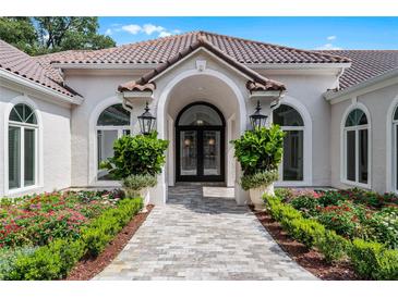 Elegant front entrance featuring a tiled walkway, double doors, lush landscaping, and a stylish arched entryway at 1306 Sweetwater Club Blvd, Longwood, FL 32779