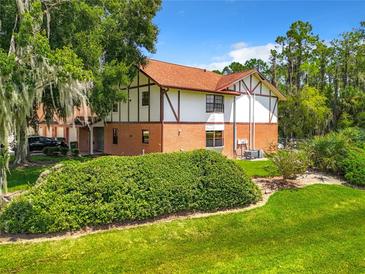 Brick building with a red tile roof, surrounded by lush landscaping and green grass at 100 E Oak Terrace Dr # G1, Leesburg, FL 34748