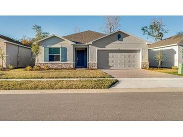 Charming single-Gathering home featuring stone accents, neutral color palette, well-manicured lawn, and a two-car garage at 349 River Front Way, Edgewater, FL 32141