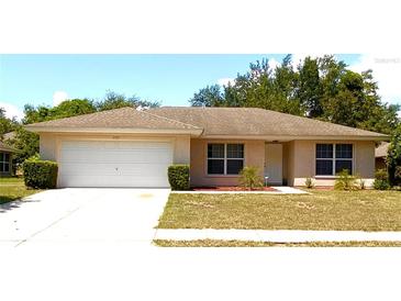 One-story house with attached garage, well-maintained lawn, and neutral color scheme at 4490 Treasure Cay Rd, Tavares, FL 32778