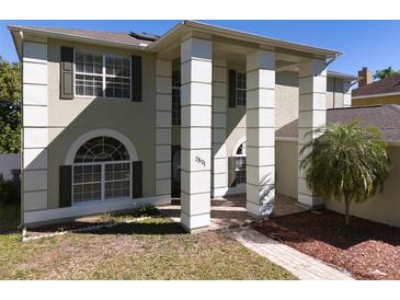 Charming home featuring stately columns, a manicured lawn, and a welcoming brick pathway at 7801 Belvoir Dr, Orlando, FL 32835