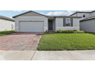Charming one-story home with a well-manicured lawn, brick driveway, and gray trim at 1542 Mermaid Way, Haines City, FL 33844