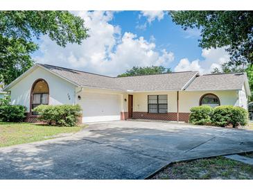 One-story house with a white exterior, brick accents, and a two-car garage at 106 Summerhill Ct, Minneola, FL 34715