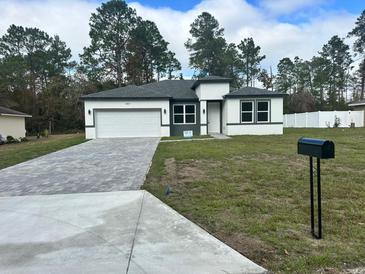 New construction home with gray and white exterior, paved driveway, and landscaped lawn at 6807 Sw 153Rd Place Rd # 6807, Ocala, FL 34473