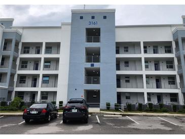 Modern condo building featuring balconies, blue accents, and ample parking for residents and guests at 3161 Paradox Cir # 202, Kissimmee, FL 34746