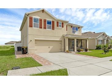 Inviting two-story home featuring red shutters, a two-car garage, screened in porch, and well-maintained landscaping at 205 Hamlet Rd, Davenport, FL 33837