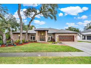 Charming brick home with well-manicured lawn, mature trees and a two-car garage on a sunny day at 250 Shady Oaks Cir, Lake Mary, FL 32746