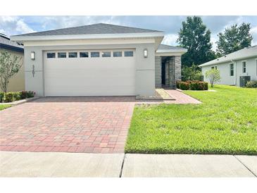 Single-story home with a two-car garage and landscaped lawn at 3201 Songbird Cir, Harmony, FL 34773