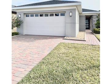 Modern home with white garage door, paver driveway, and landscaped lawn at 3201 Songbird Cir, Harmony, FL 34773