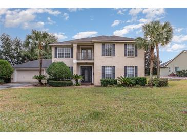 Two-story house with gray shutters, palm trees, and a well-manicured lawn at 105 James Pond Ct, Debary, FL 32713
