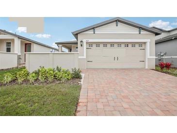 Charming home featuring a two-car garage and a beautifully landscaped front yard with a brick paved driveway at 507 Kennedy Dr, Lake Alfred, FL 33850