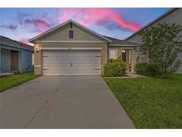 Tan house with white garage door and landscaping; sunset in background at 2321 Tay Wes Dr, Saint Cloud, FL 34771