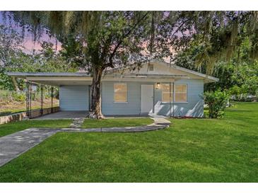 Light blue house with covered carport and a spacious lawn at 423 E 9Th St, Frostproof, FL 33843